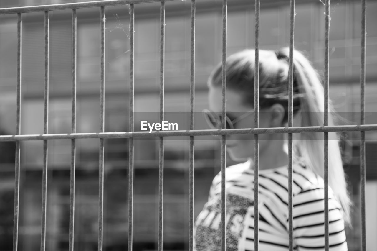 Young woman seen through fence