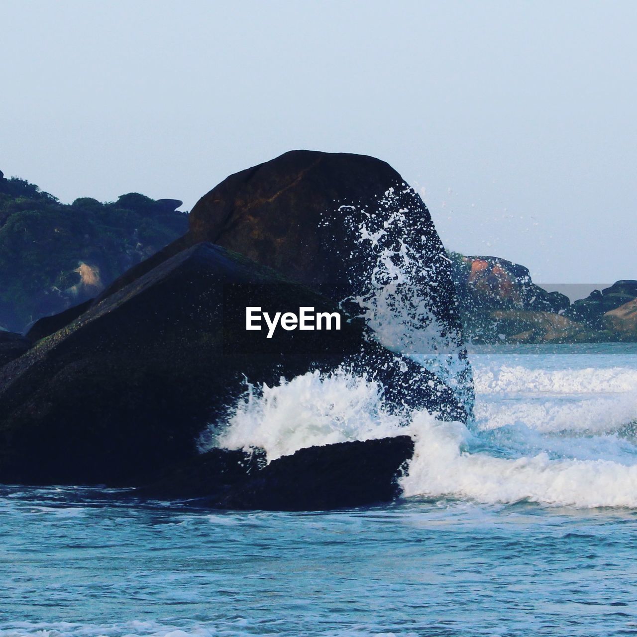 WAVES SPLASHING ON ROCKS AGAINST CLEAR SKY