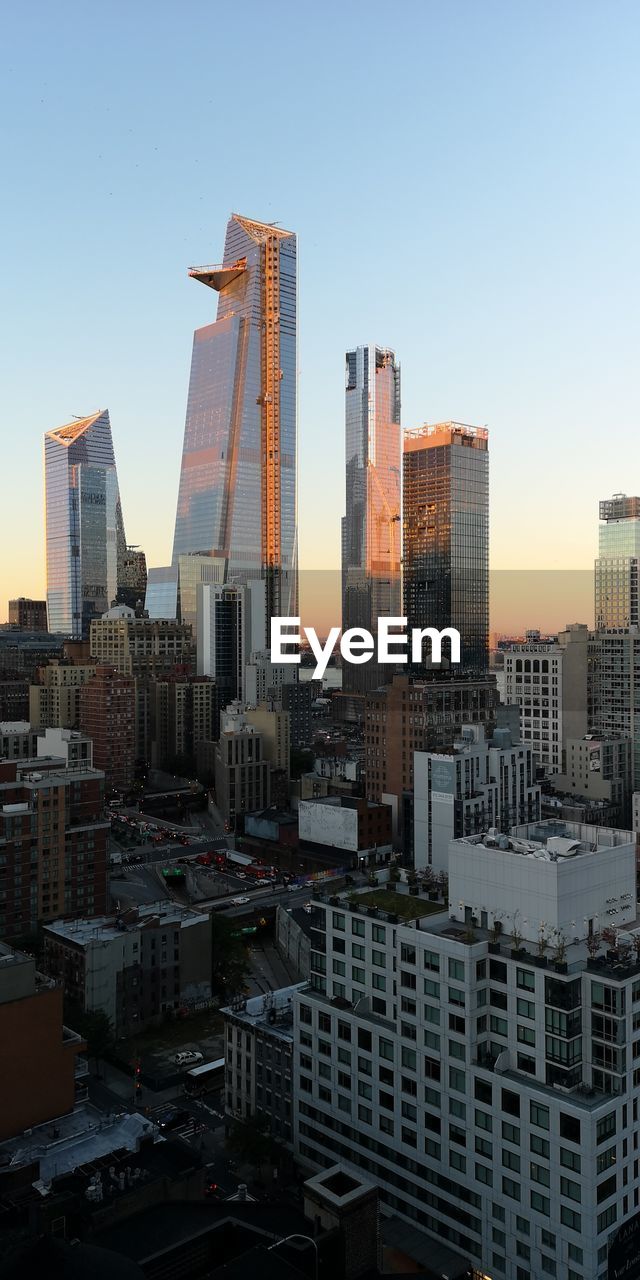Modern buildings in city against sky during sunset