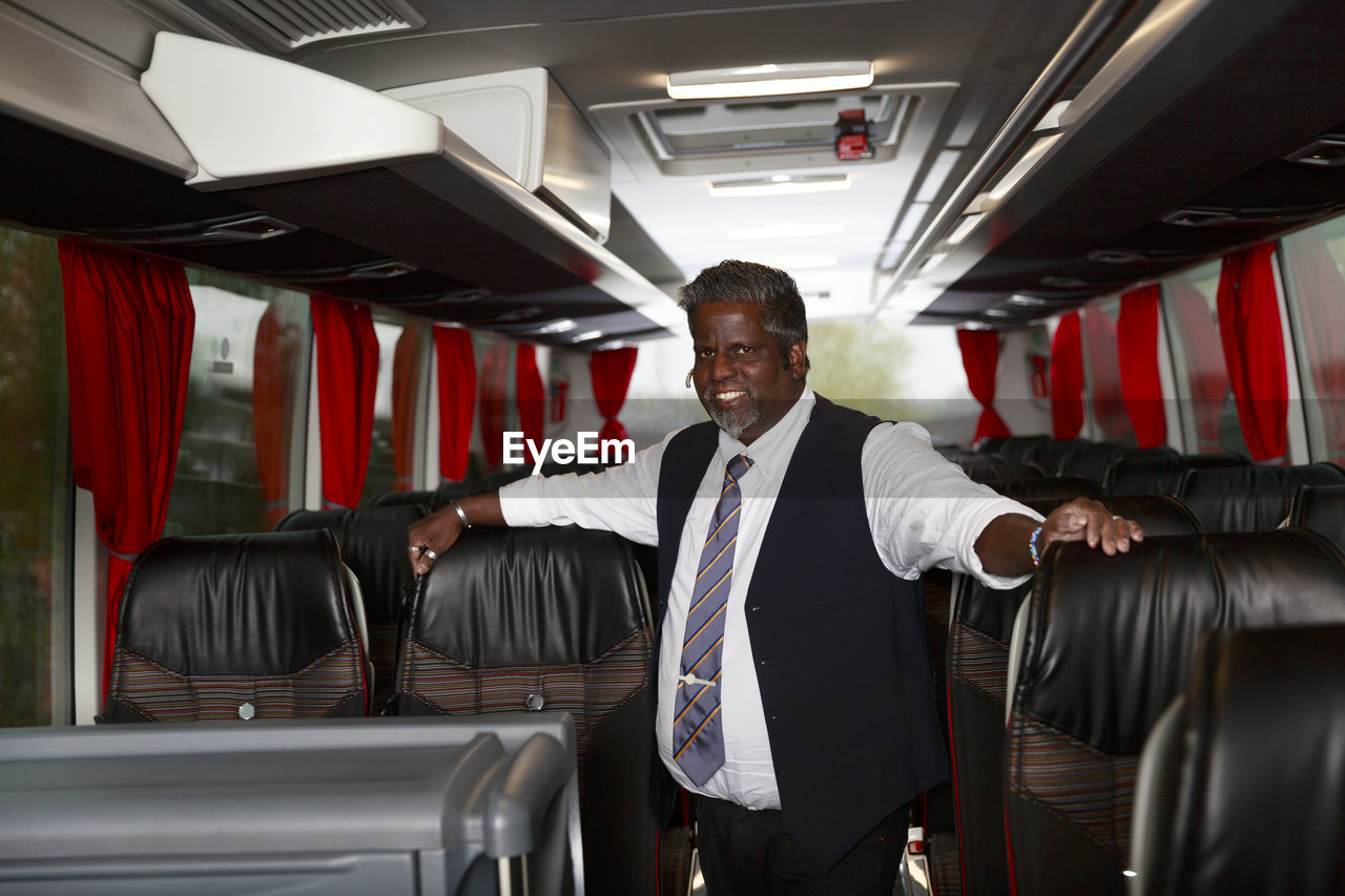 Smiling driver standing in bus