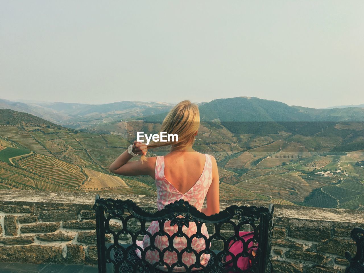 Rear view of woman sitting on chair at observation point against landscape