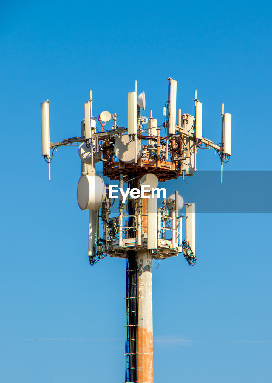 Low angle view of communications tower against clear blue sky