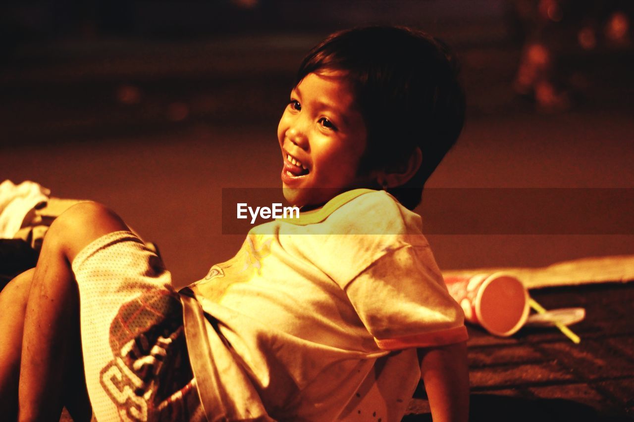 Smiling boy looking away while sitting on ground