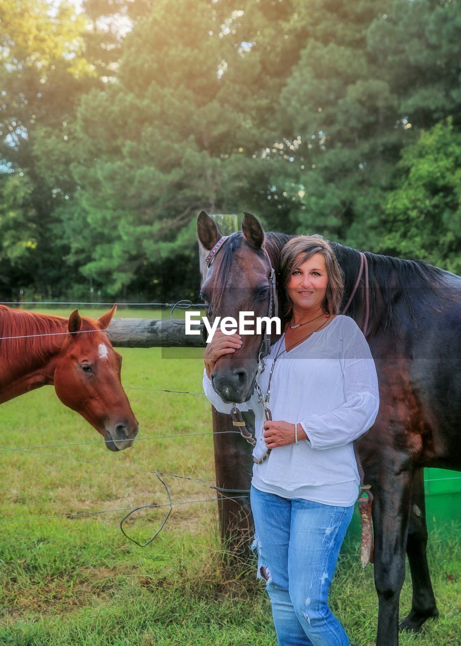 Portrait of woman with horses standing on field