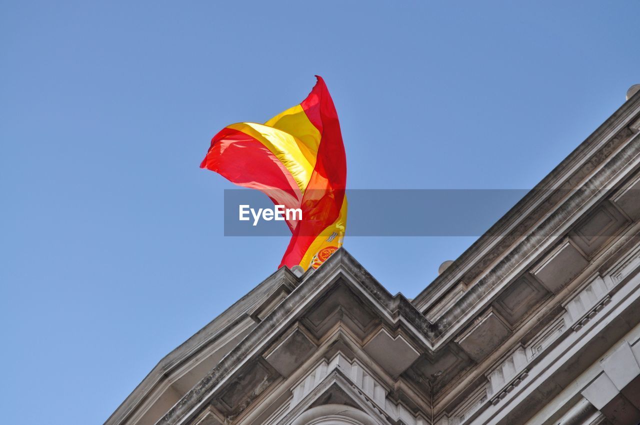 Low angle view of spanish flag on historic building against clear sky