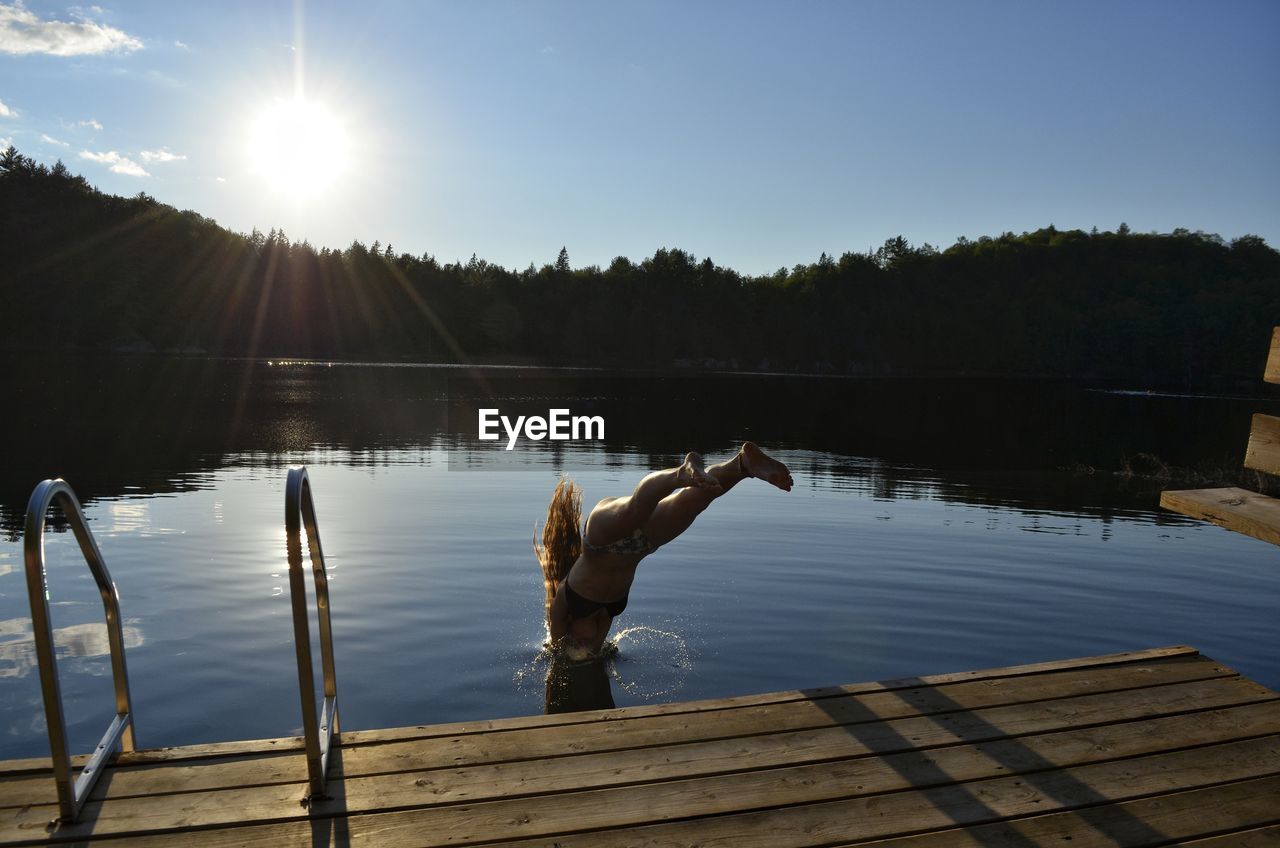 REFLECTION OF MAN ON PIER IN LAKE