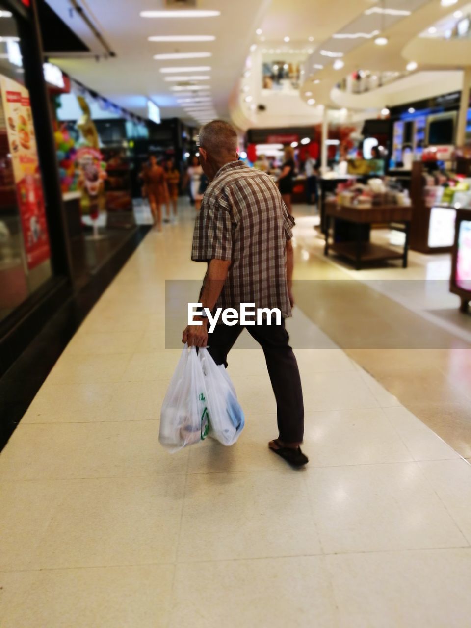 FULL LENGTH REAR VIEW OF MAN WALKING IN ILLUMINATED UNDERGROUND