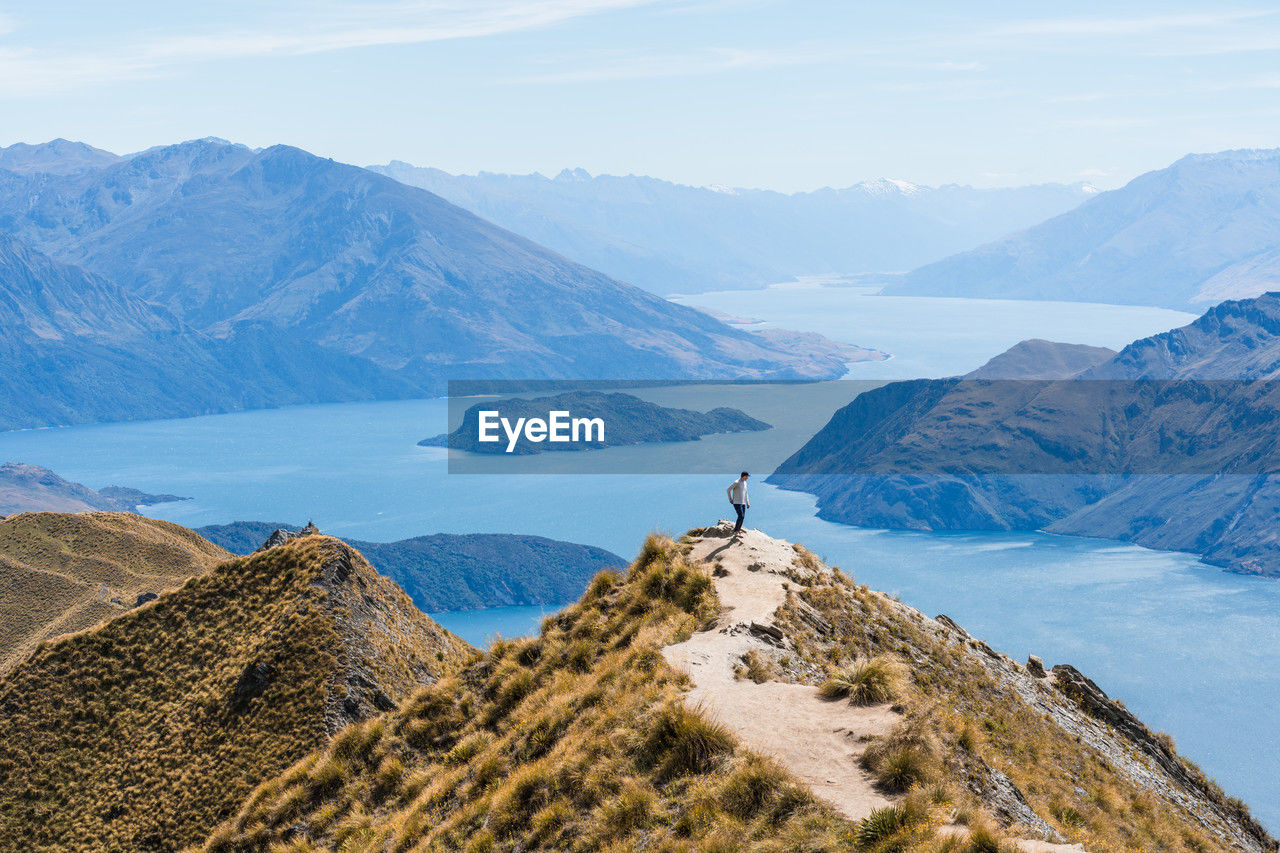Man hiking amongst mountain views from the roys peak trail, new zealand