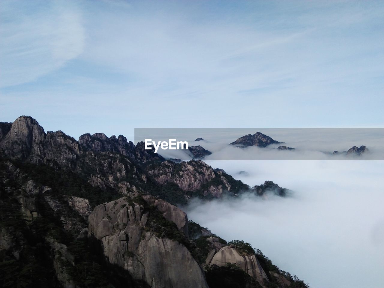 Scenic view of mountains amidst fog against sky