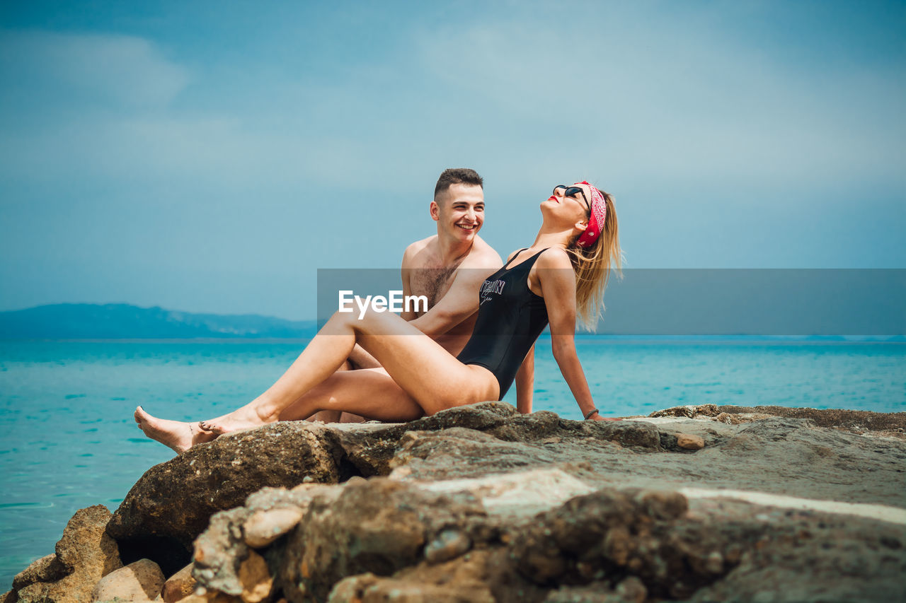 Young couple spending leisure time at beach against sky