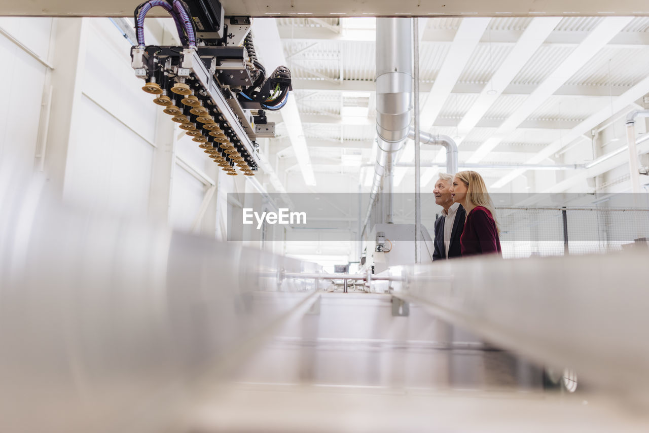 Manager and colleague looking at machine in factory