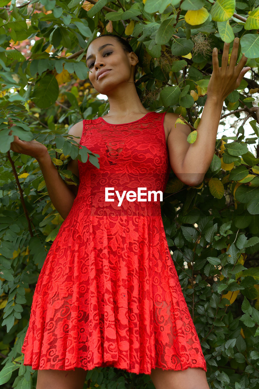 Portrait of young woman standing against plants