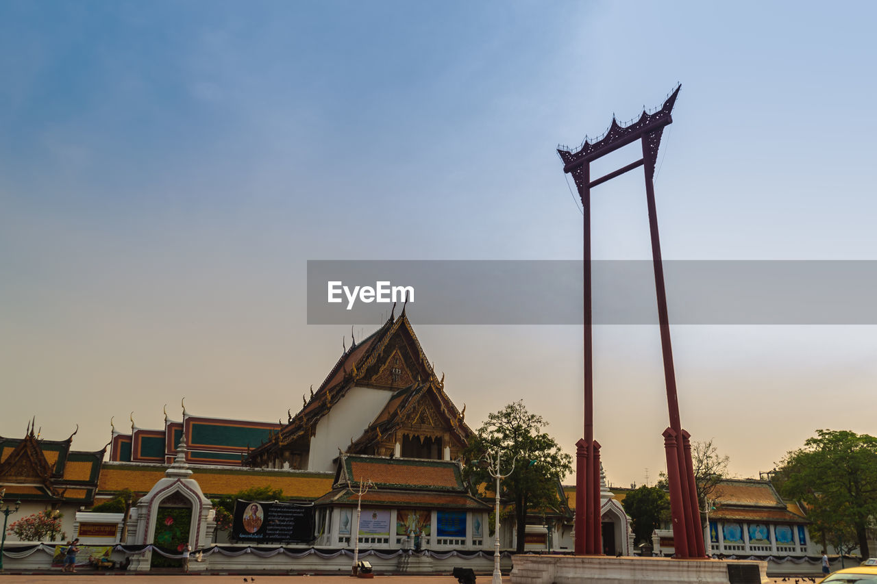 LOW ANGLE VIEW OF TRADITIONAL BUILDING BY TREES AGAINST SKY