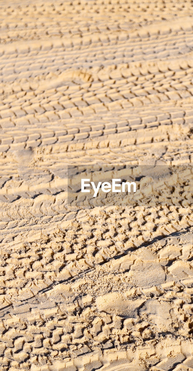 CLOSE-UP OF TIRE TRACKS ON SAND