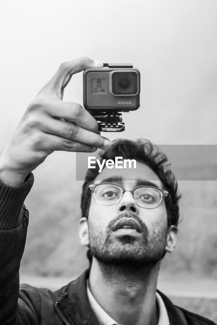 Close-up of man looking at camera against sky