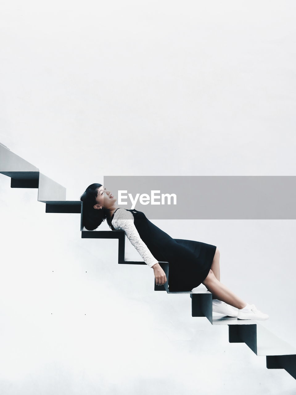 Young woman lying on steps against white background