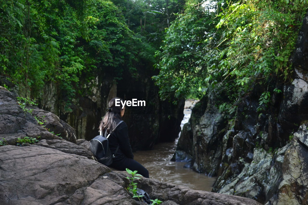 Woman sitting on rock by river