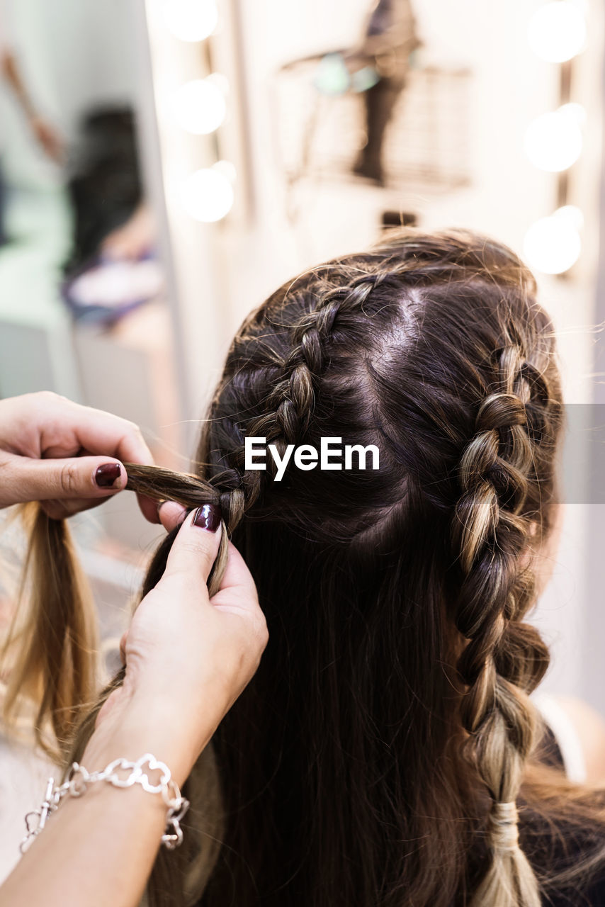 Hairdresser making braids to a young client at hairdresser salon