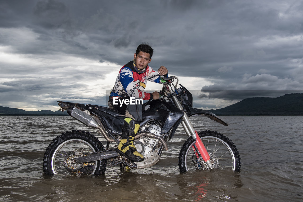 Man posing on his dirt-bike in a lake near pak chong / thailand