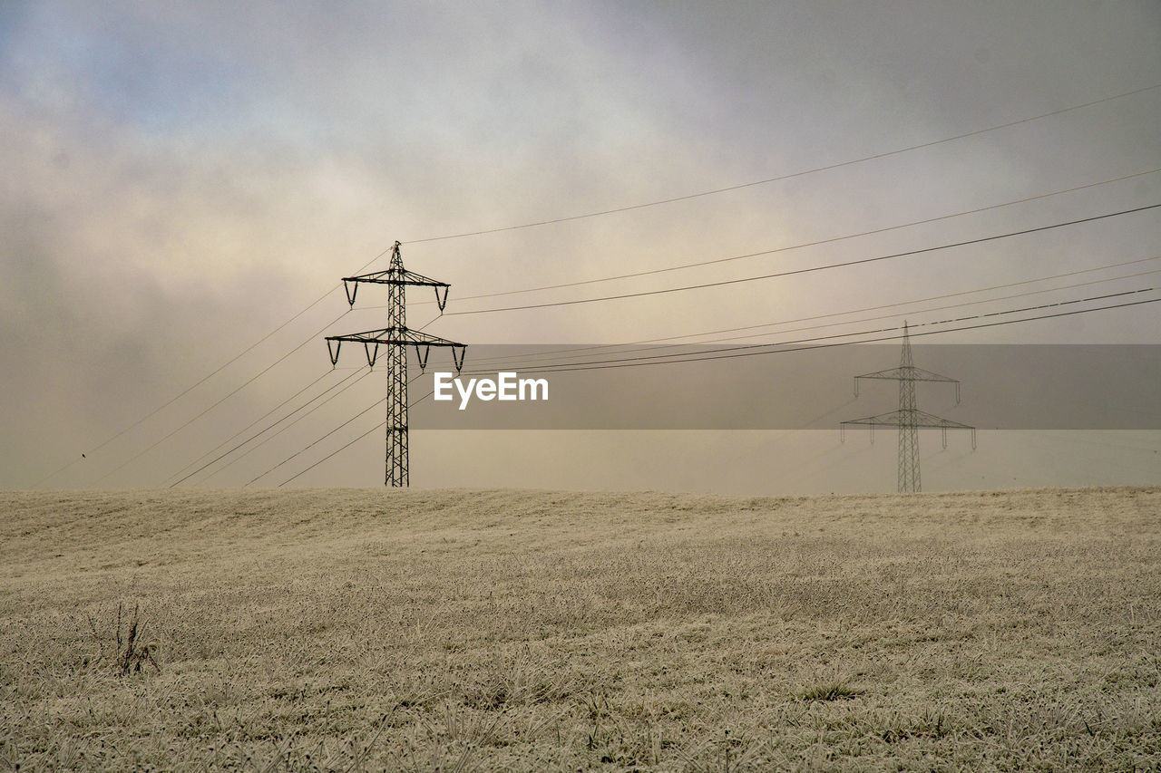 ELECTRICITY PYLON ON FIELD AGAINST SKY DURING SUNSET