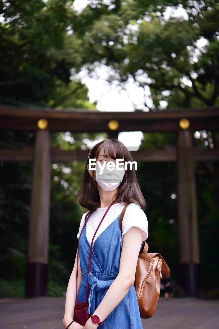 Portrait of girl standing against trees