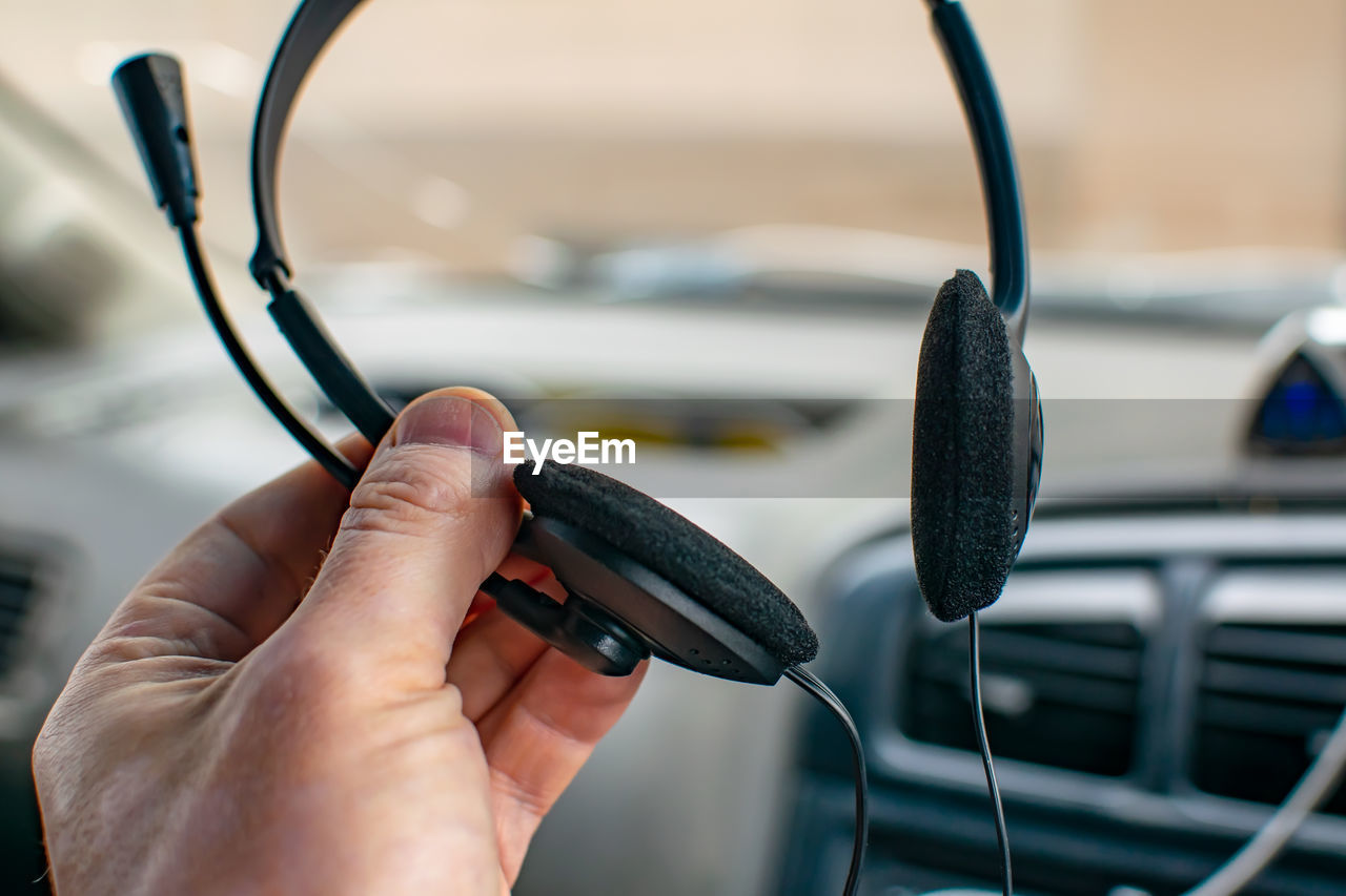 View of stereo headphones with soft foam pads with a microphone in the hand of a person, a driver