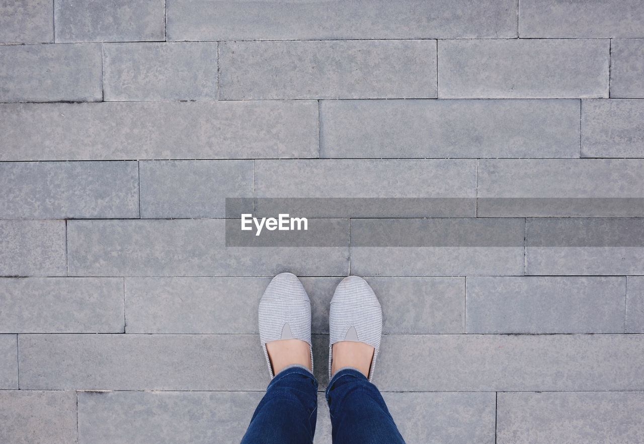 Low section of woman standing on footpath