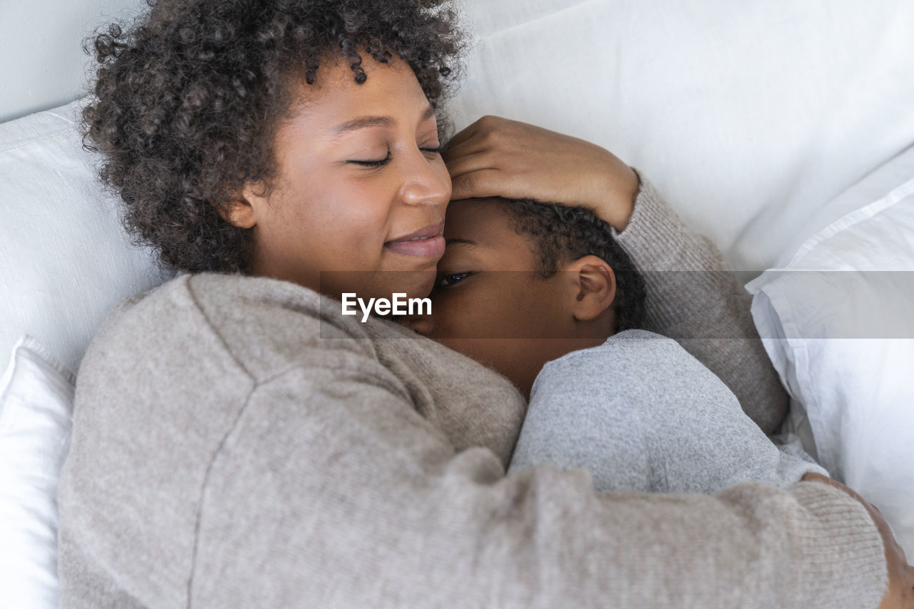 Son sleeping in mother's arms at home