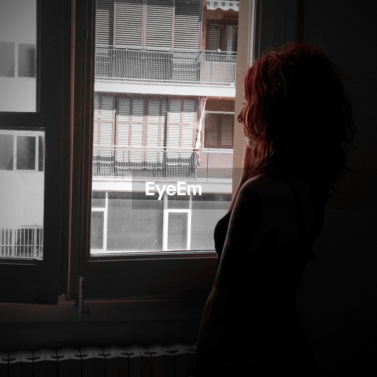 Rear view of woman looking towards window at home