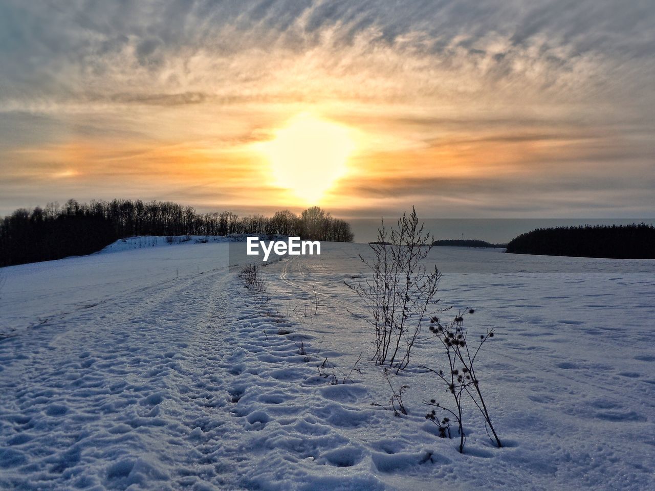 Scenic view of frozen landscape against sky during sunset