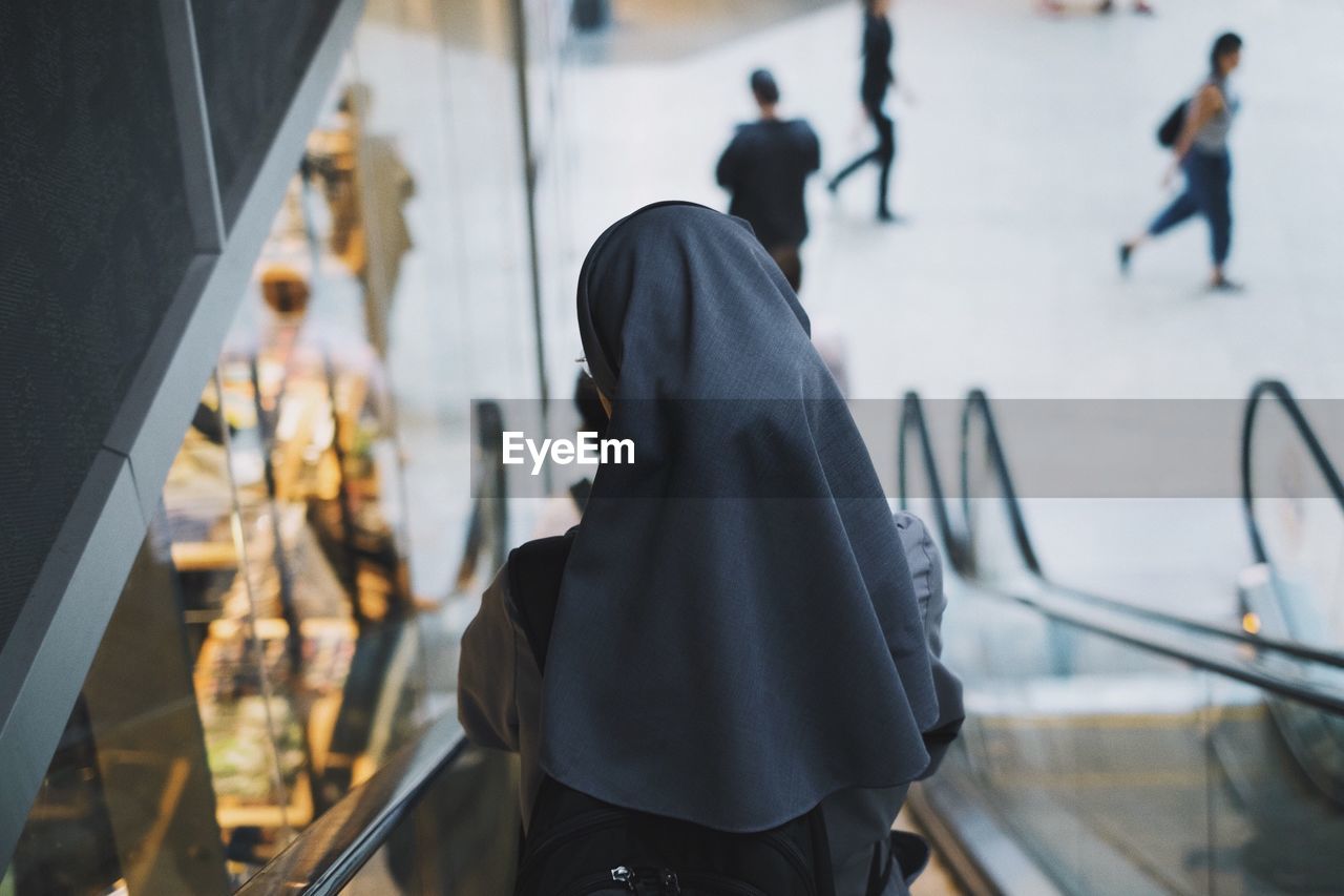 Rear view of a nun on escalator