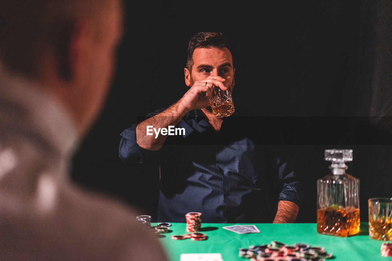 Man drinking alcohol while playing poker