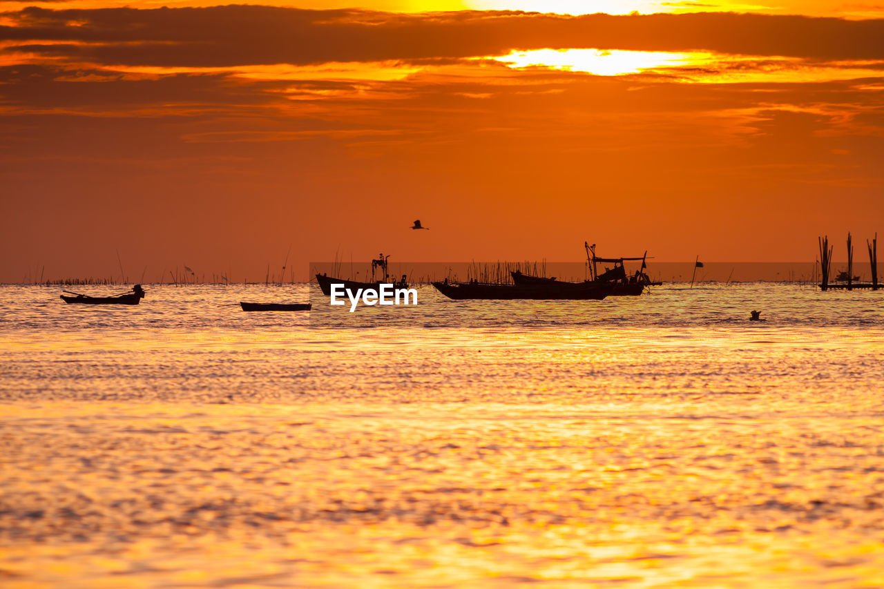 Silhouette boats sailing in sea against sky during sunset