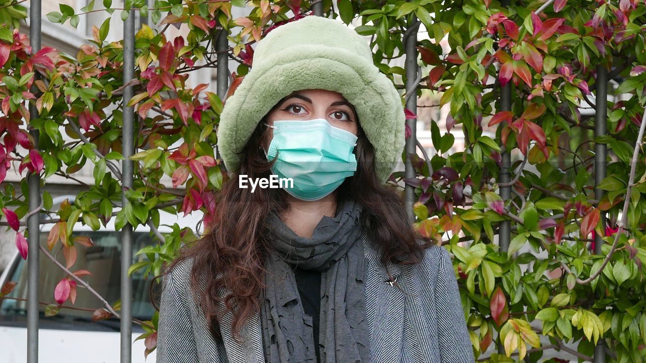 Portrait of young woman standing against plants