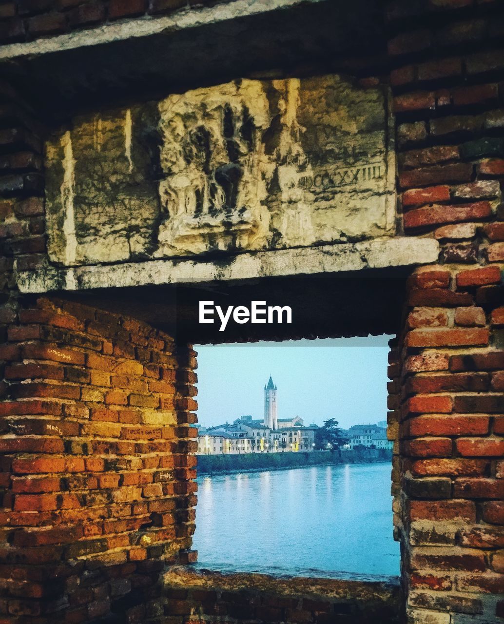 Buildings and sea seen through window on brick wall