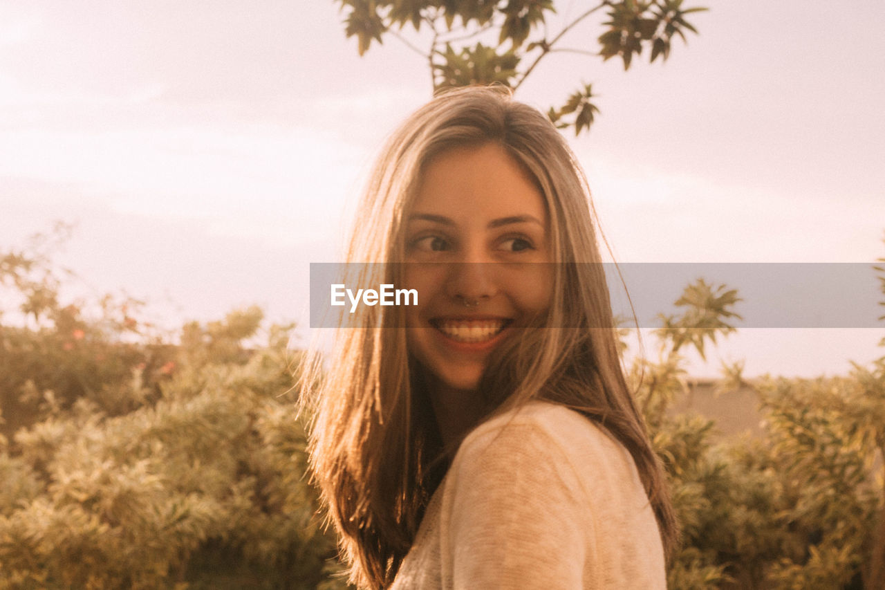 Side view of smiling young woman looking away