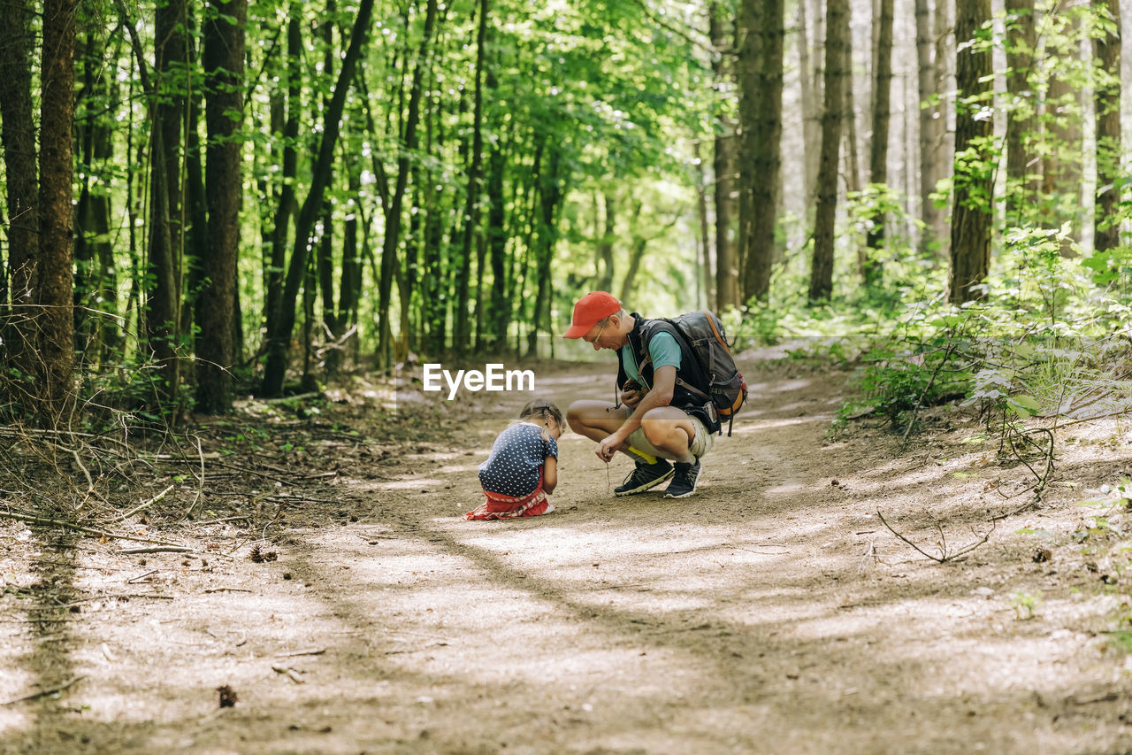 Father and daughter crouching in forest