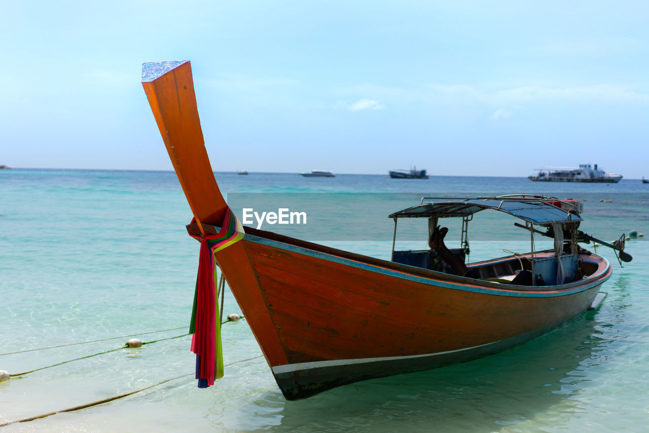 Longtail boat in sea against sky