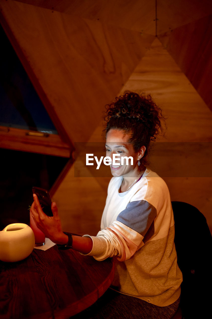 Woman using a mobile phone while relaxing in a dome tent.