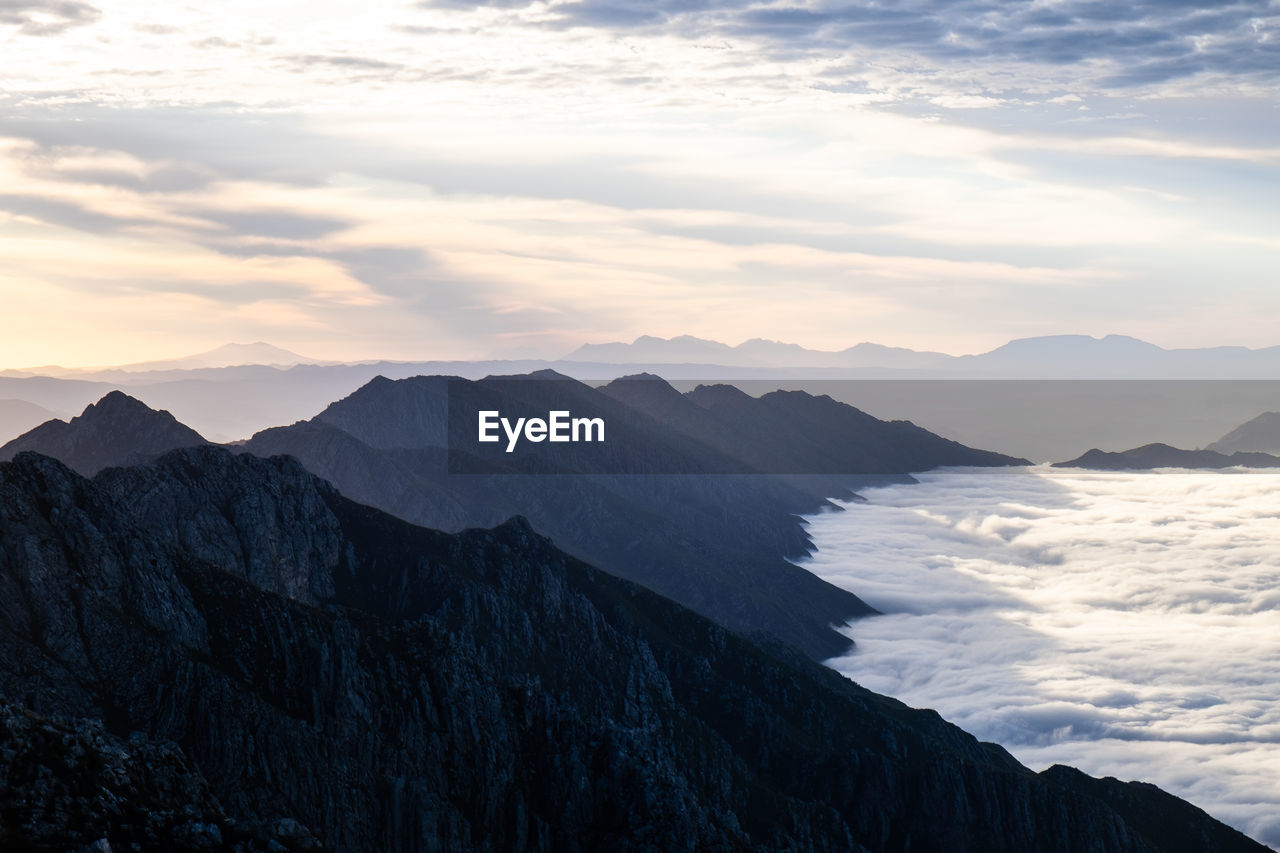 Distant view of mountain ridges at sunrise with sea of clouds 