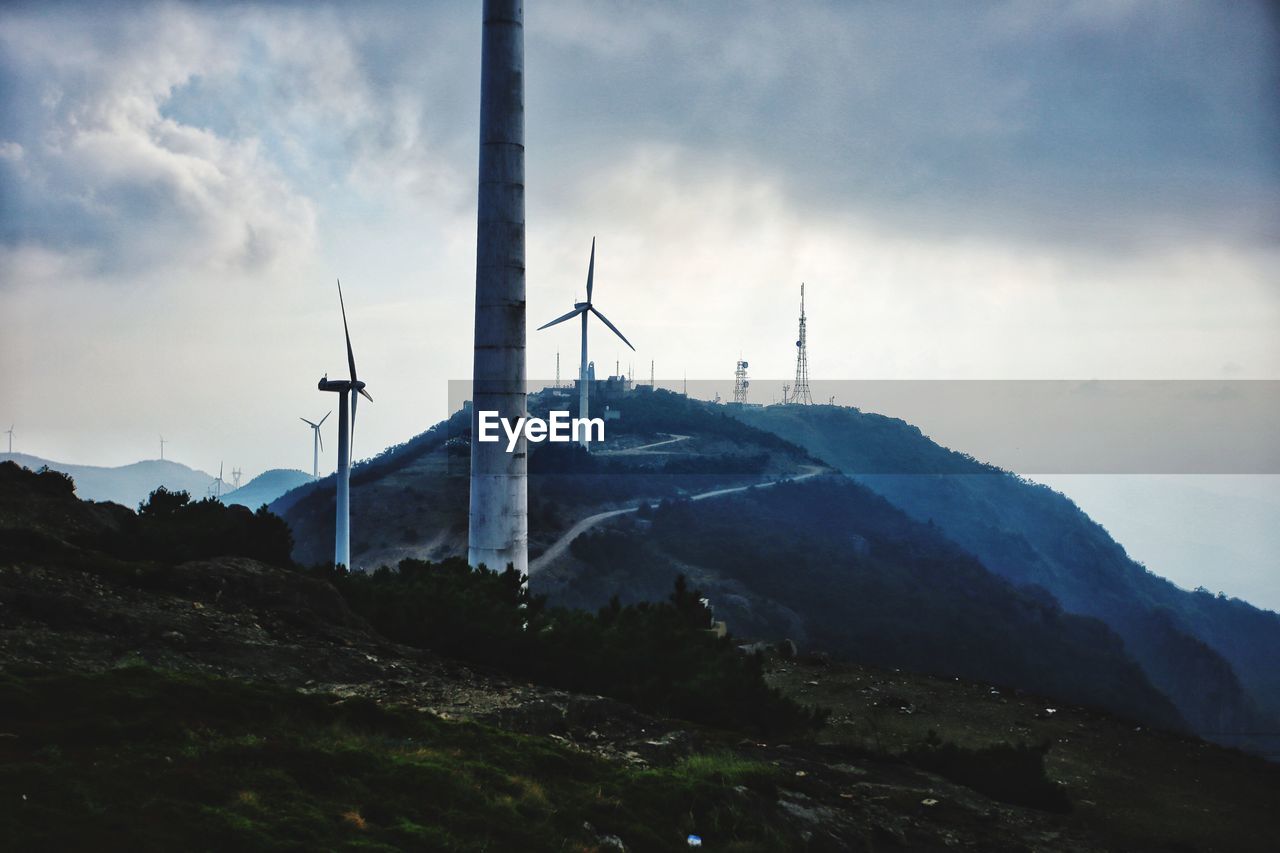 WIND TURBINES IN MOUNTAINS AGAINST SKY