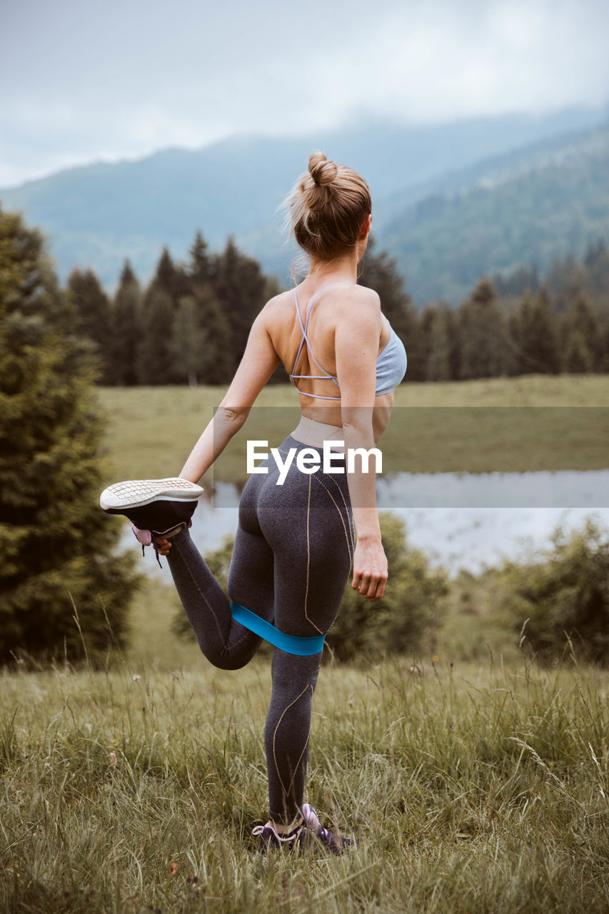 REAR VIEW OF WOMAN WALKING ON FIELD