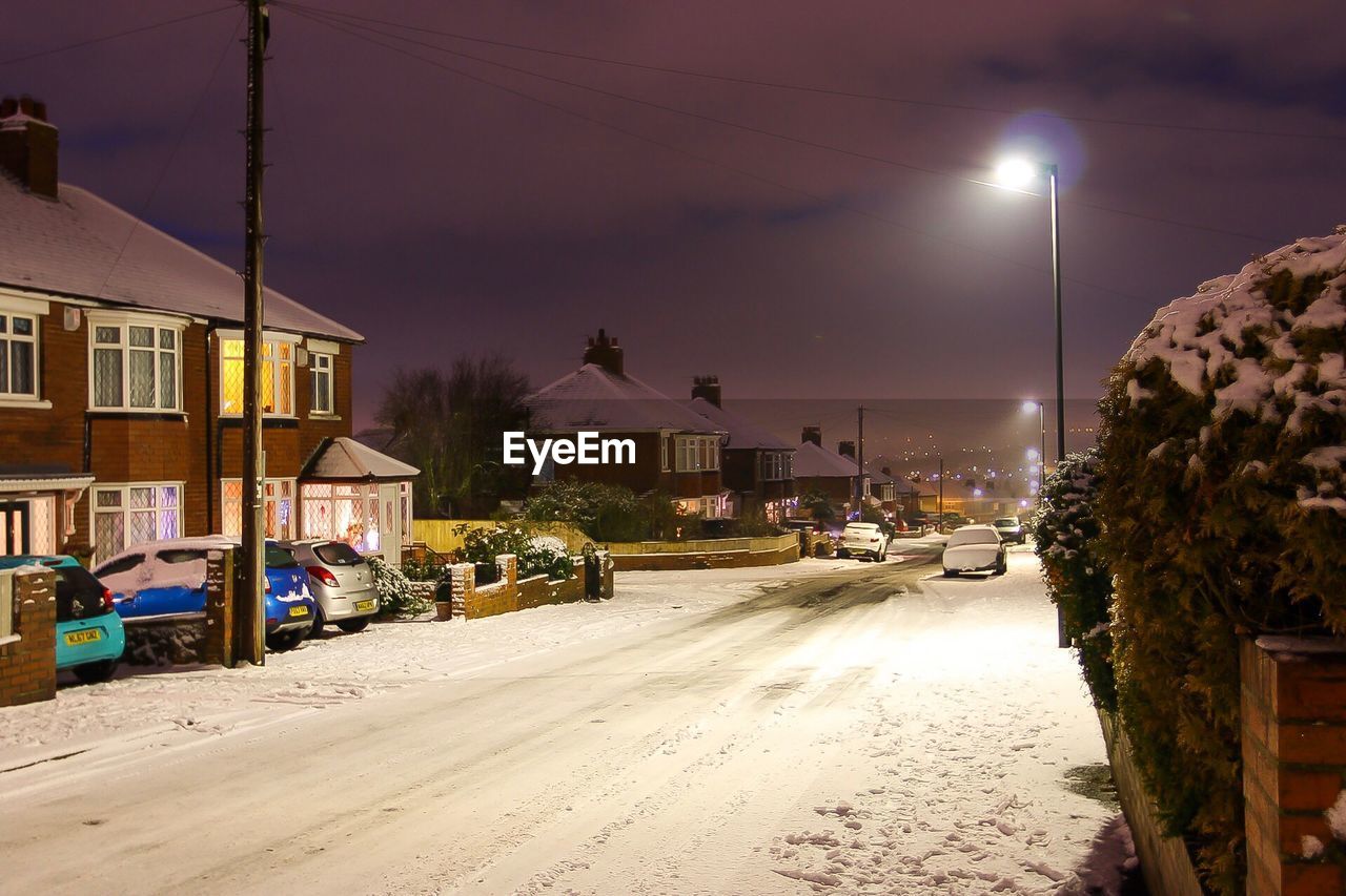 ILLUMINATED STREET AGAINST SKY DURING WINTER