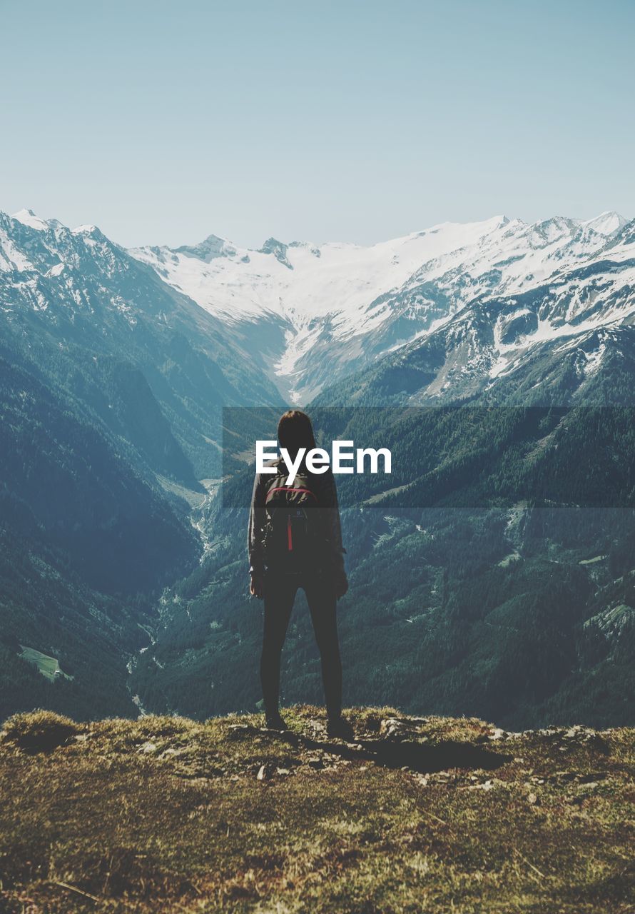 Rear view of woman standing on mountain against sky