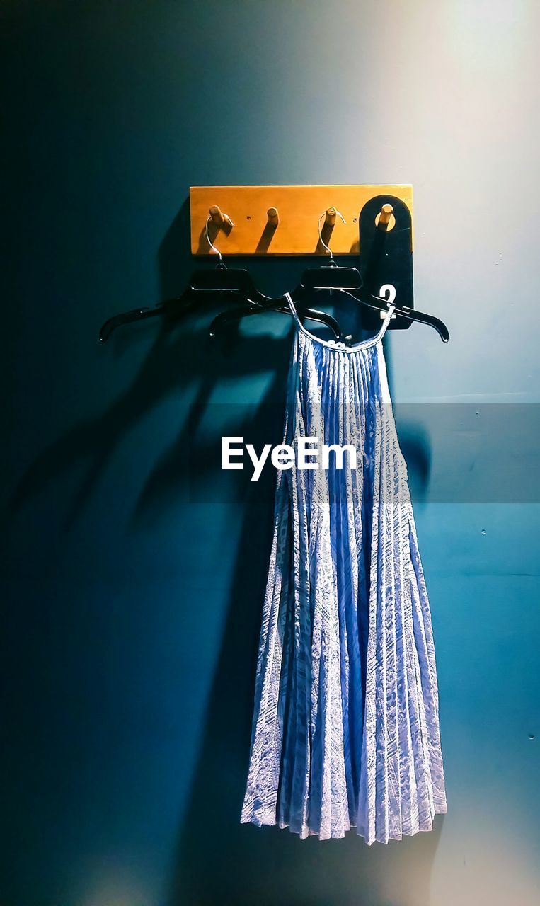 Blue dress hanging on coathanger from hook on wall