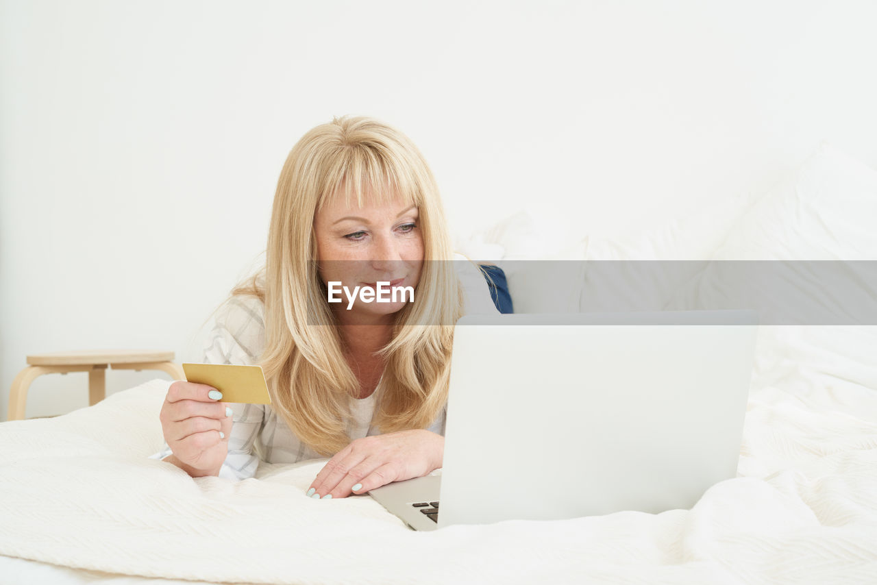 Middle age female on online shopping. portrait of mature blond woman is holding credit card