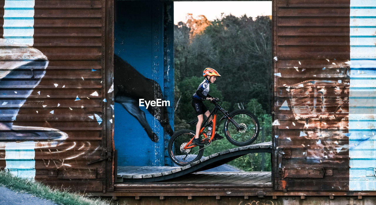 FULL LENGTH OF MAN CYCLING ON BUILDING