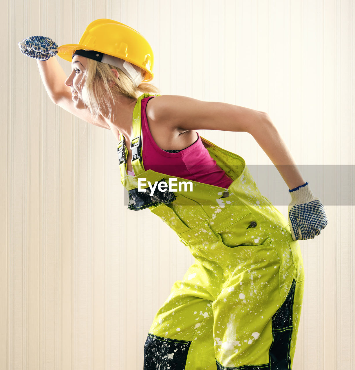 Female worker in coverall looking away while standing against wall