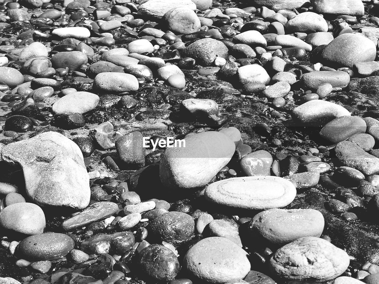 HIGH ANGLE VIEW OF PEBBLES ON BEACH