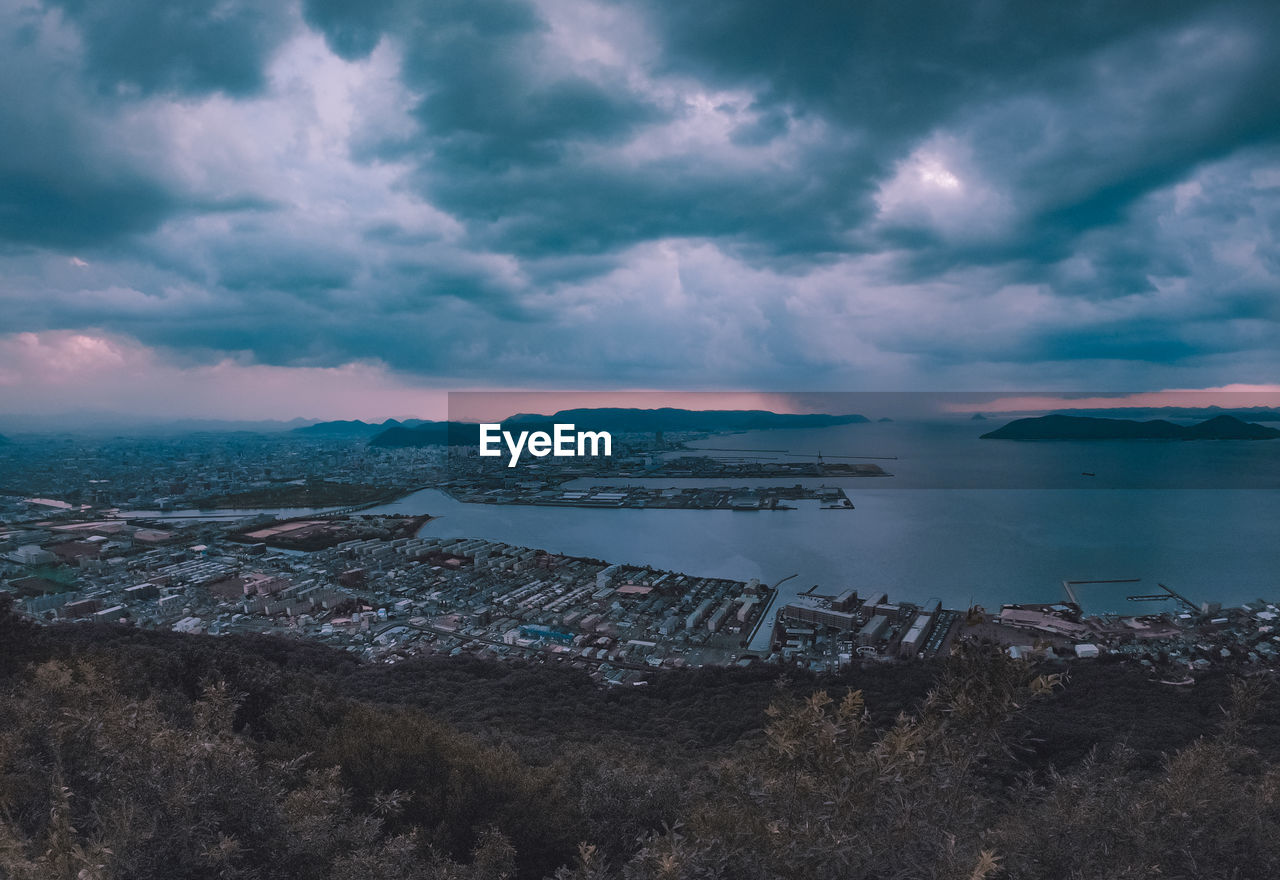 Aerial view of city by sea against sky